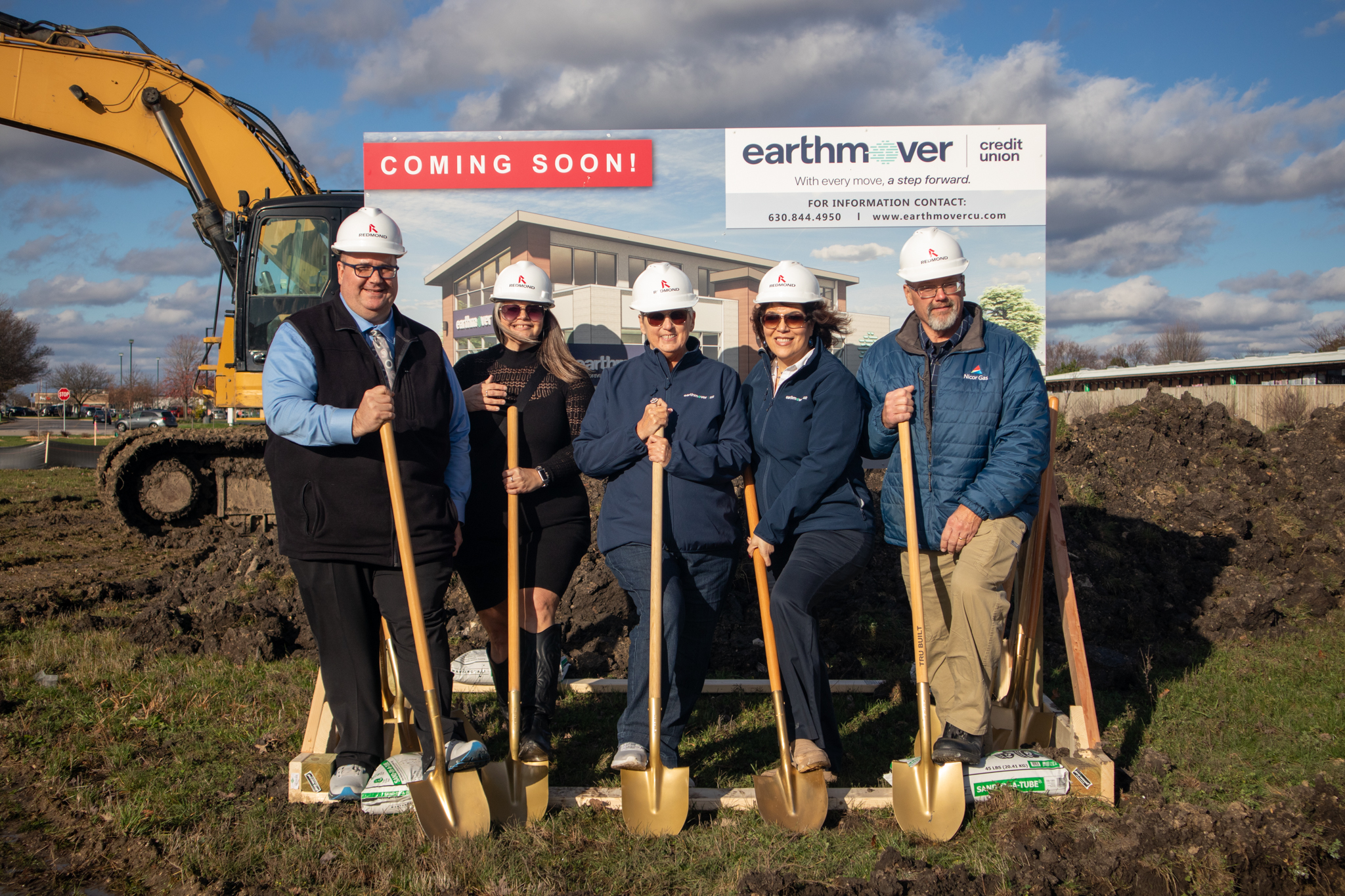 Four people posing with shovels